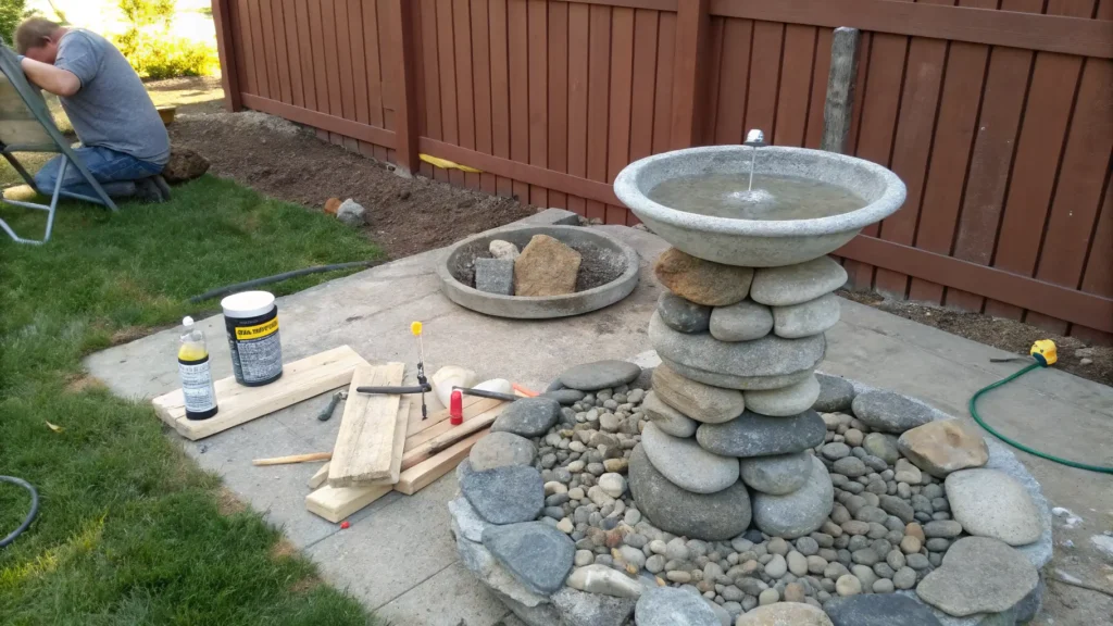 Step-by-step photos illustrating the construction of a stacked stone DIY bird bath.